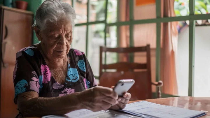 Como Solicitar Ressarcimento da Fraude no INSS 1 Idosa brasileira usando celular para solicitar ressarcimento no INSS.